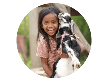 Kleines Mädchen freut sich über sie erste Ziege, die se von World Vision bekommen hat