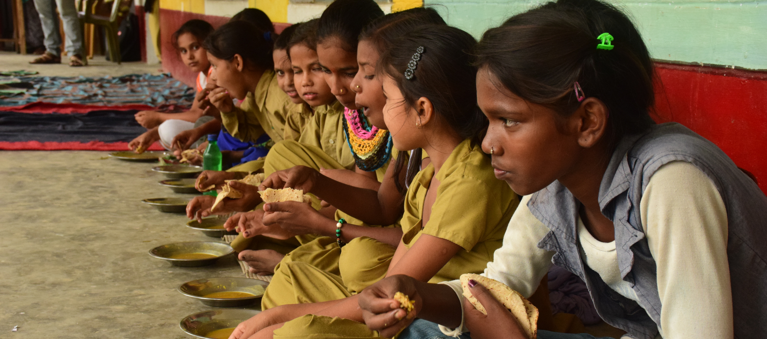 Mädchen in Indien bei einer Schulmahlzeit mit Linsen und Brot