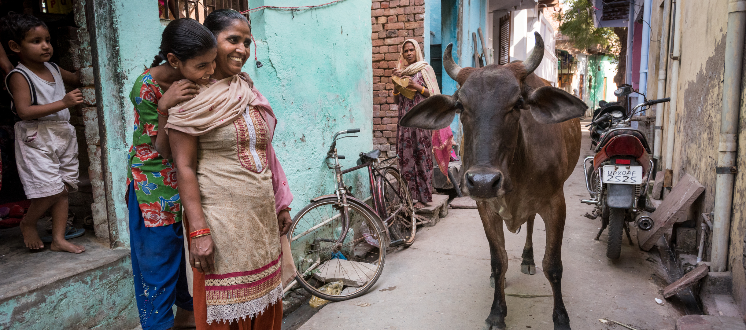 Straßenszene in der indischen Stadt Agra mit Kuh und Menschen