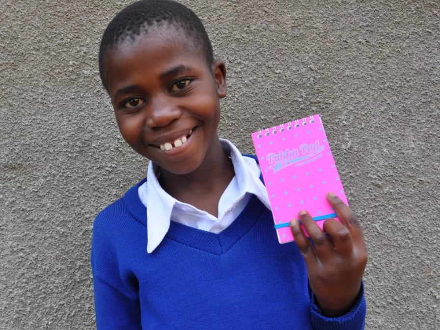 Florence aus Tansania mit einem Notizbuch von ihrem Paten.