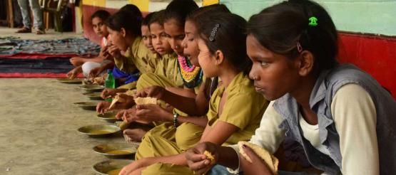 Mädchen in Indien bei einer Schulmahlzeit mit Linsen und Brot