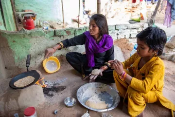 Mutter bereitet mit ihrem Kind Essen zu in Indien