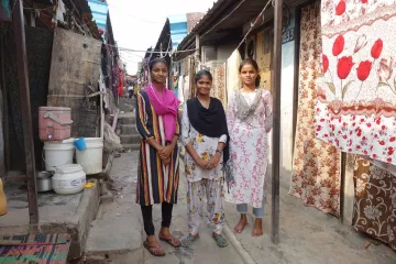 Drei Mädchen in einer Häuserstraße in Indien