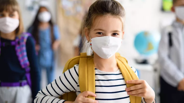 Schulkind mit Maske zum Schutz gegen COVID-19