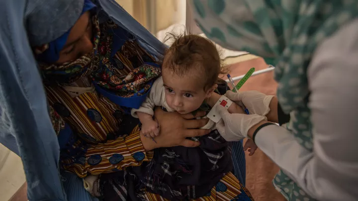 An der roten Farbe des Oberarm-Messbandes erkennt  eine medizinische Helferin in Afghanistan, dass das Baby akut unterernährt  ist und dringend Hilfe benötigt.