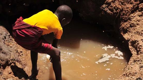 Junge holt verschmutztes Trinkwasser